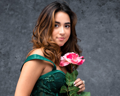 Beautiful Girl holding a Rose In Green Dress On Dark Background. 